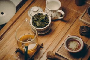 Fennel seeds in a small bowl next to a cup of herbal tea on a rustic wooden surface 